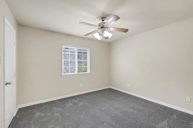 an empty room with a window and a fan