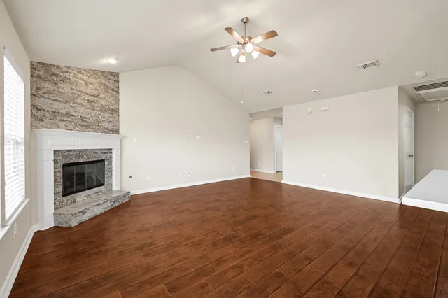 a view of an empty room with wooden floor and a fireplace