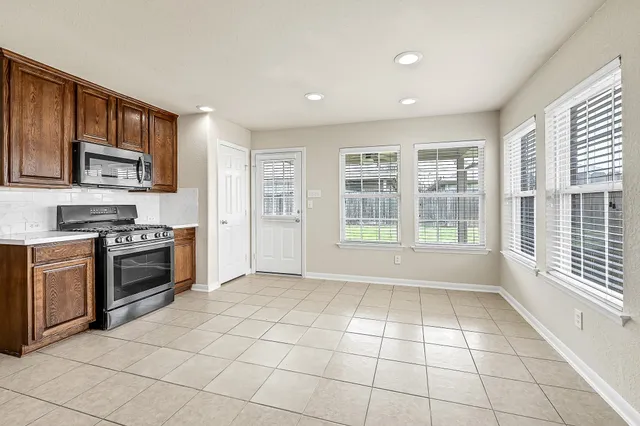 a view of kitchen with granite countertop a stove top oven a sink a counter space and cabinets