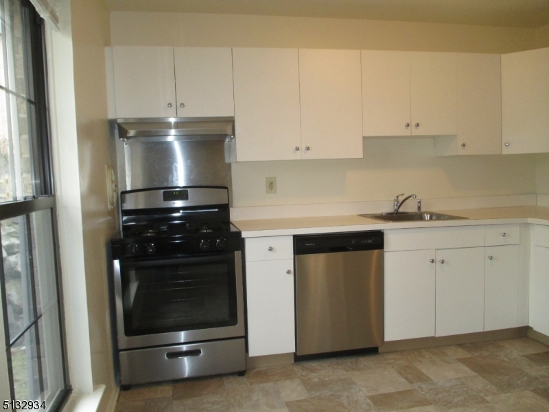 181 Long Hill Road, Unit 8 Little Falls, NJ 07424 - Photo 10 of 15 a kitchen with white cabinets and white appliances