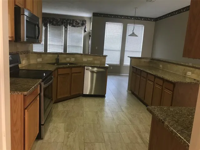 a kitchen with stainless steel appliances granite countertop a stove a sink and a microwave