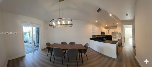 a kitchen with a dining table chairs and wooden floor