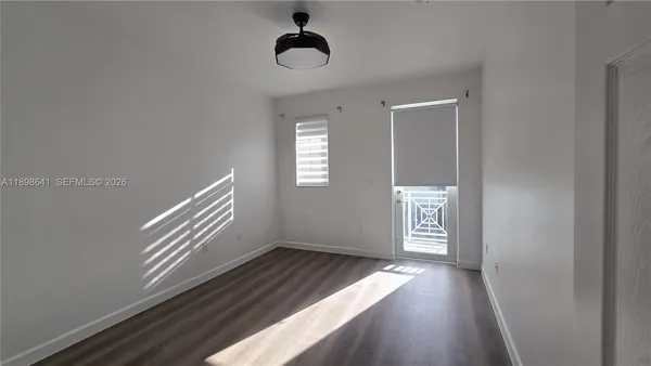 a view of an empty room with wooden floor and windows