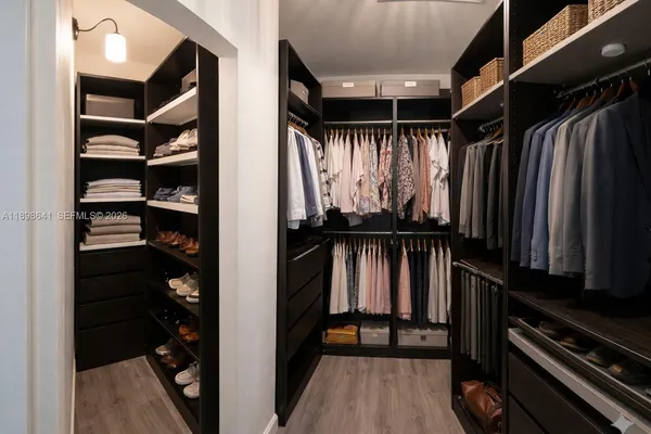 a view of walk in closet with clothes and shoes