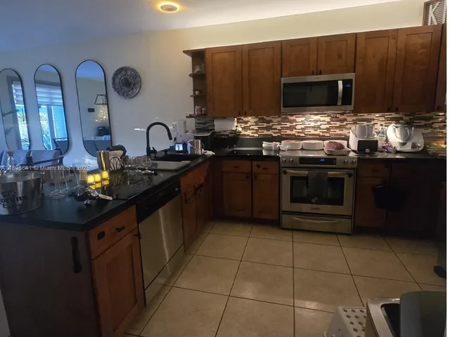 a kitchen with stainless steel appliances granite countertop a stove a sink and a microwave