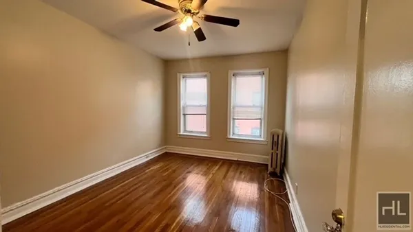 a view of empty room with wooden floor and fan
