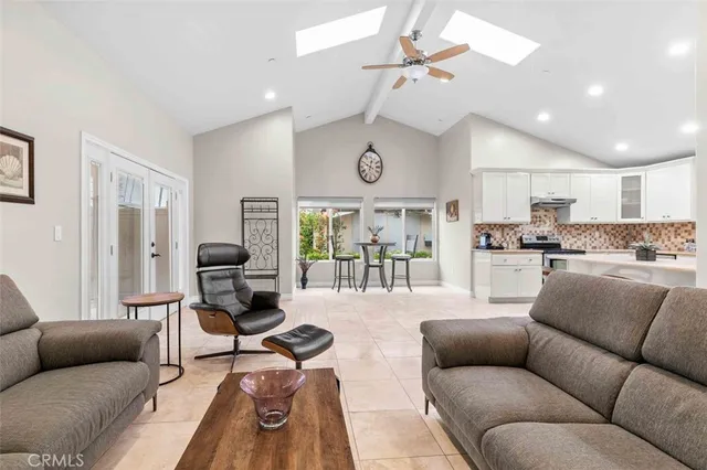 a living room with furniture kitchen view and a chandelier
