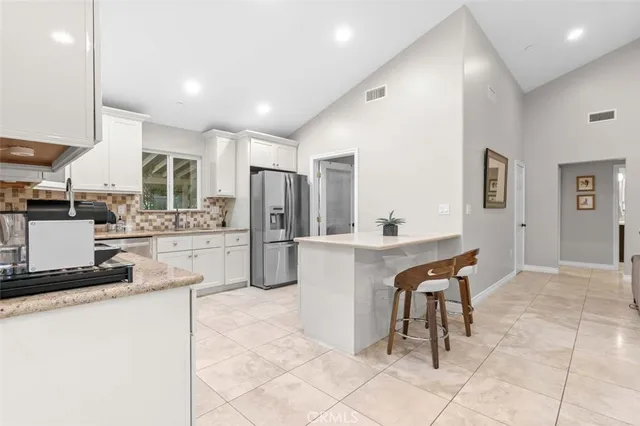 a kitchen with stainless steel appliances kitchen island granite countertop a refrigerator and a sink