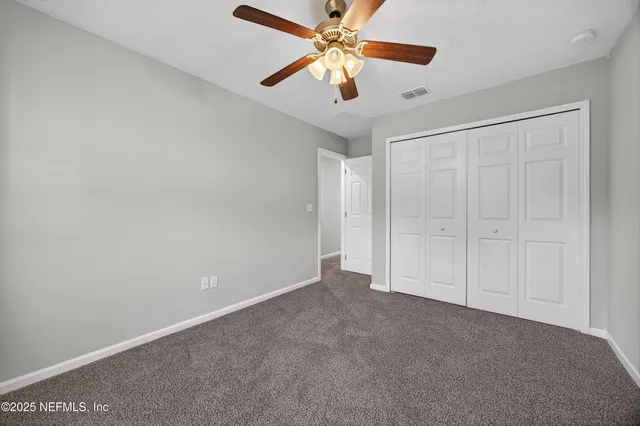 an empty room with windows and fan