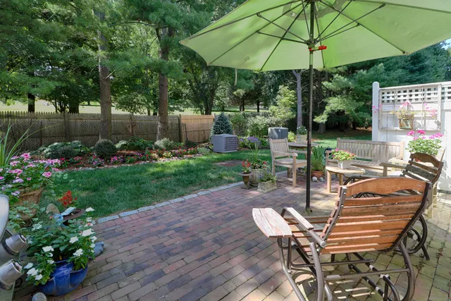 a view of a table and chairs under an umbrella in backyard