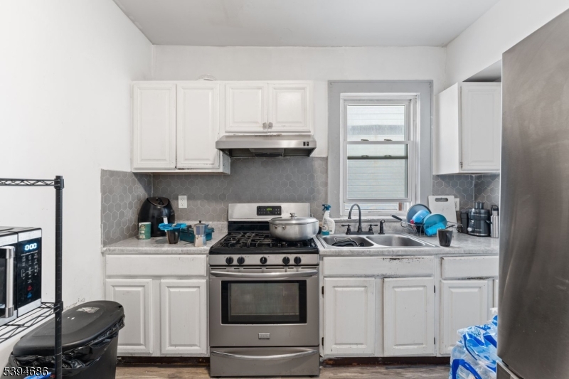 907 Flora Street Elizabeth, NJ 07201 - Photo 15 of 24 a kitchen with stainless steel appliances a white stove top oven and cabinets