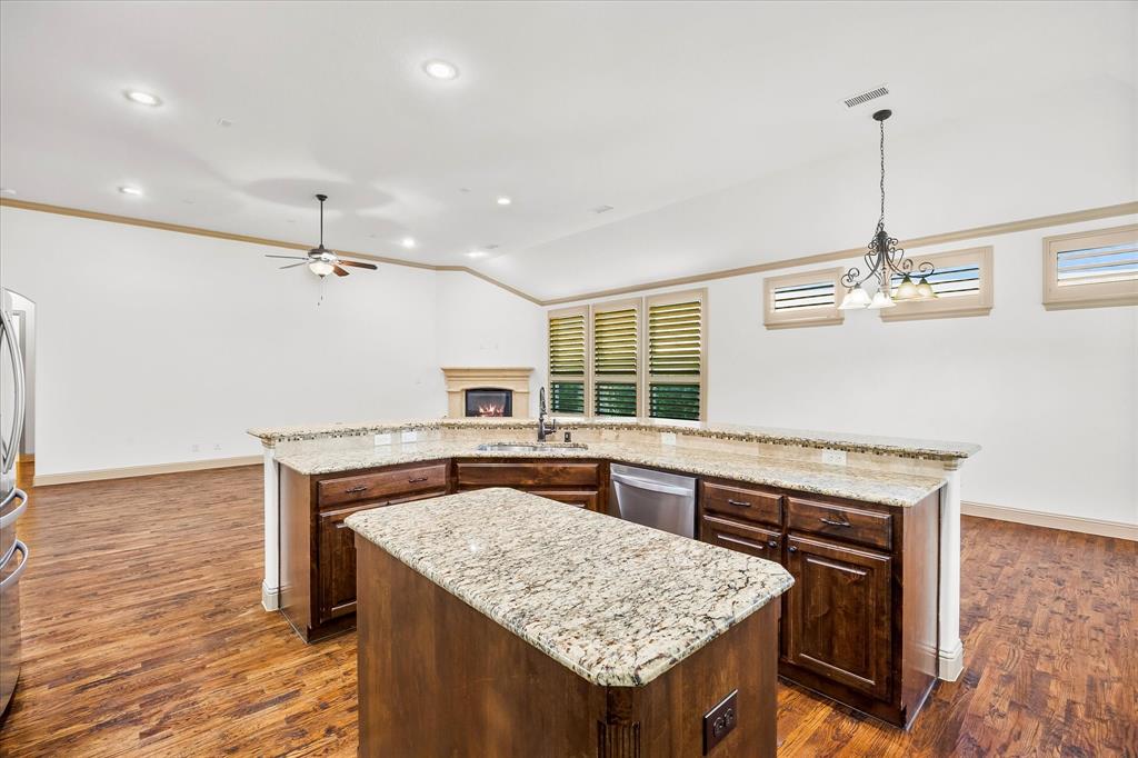 6814 Springwood Lane Garland, TX 75044 - Photo 17 of 33 a kitchen with a center island wooden floor and a ceiling fan
