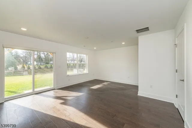 an empty room with wooden floor and a floor to ceiling window