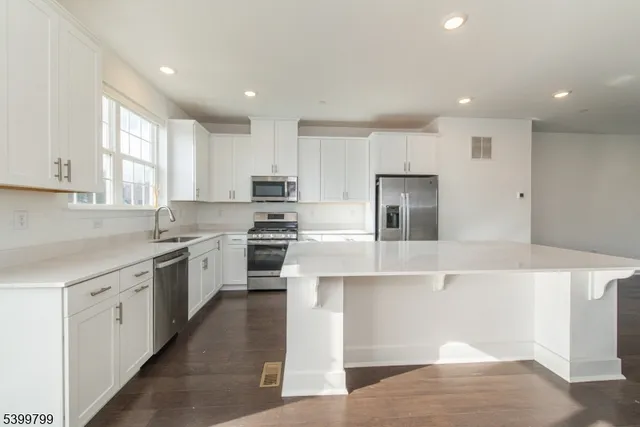 a kitchen with kitchen island white cabinets and stainless steel appliances