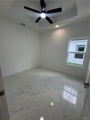 an empty room with windows and fan