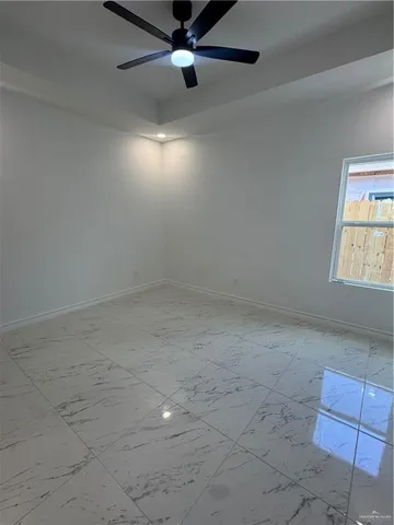 an empty room with a ceiling fan and window