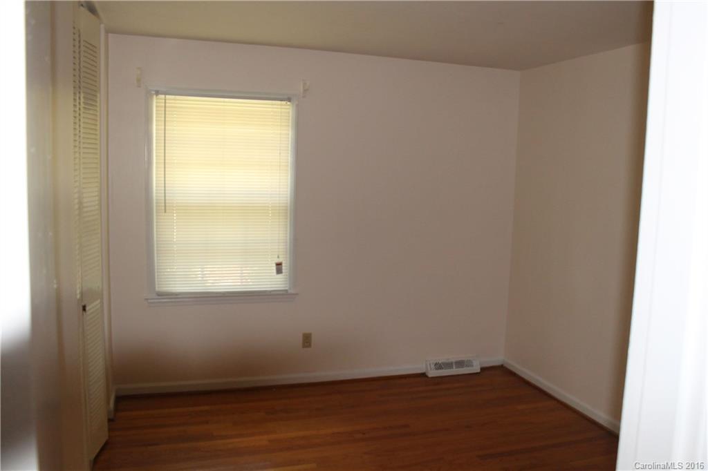 7434 Riding Trail Road Charlotte, NC 28212 - Photo 8 of 12 an empty room with wooden floor and a window