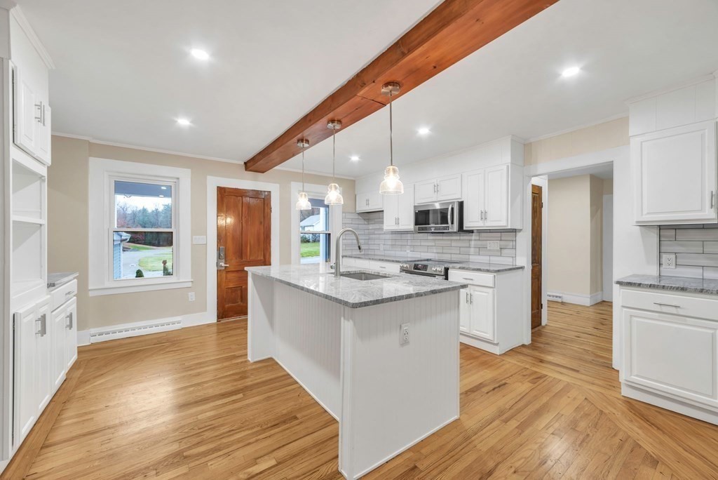 1385 Lyon Street Ludlow, MA 01056 - Photo 7 of 35 a large kitchen with stainless steel appliances kitchen island granite countertop a stove and a sink