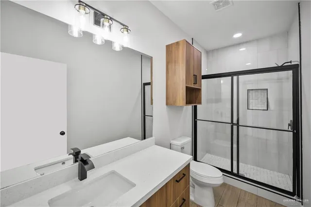 a bathroom with a sink a toilet a mirror and shower