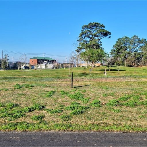 a big yard with lots of green space and trees in the background