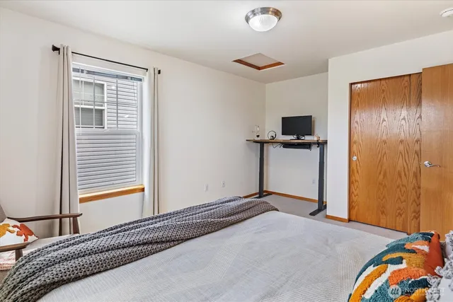 a bedroom with a bed and a flat tv screen on dresser