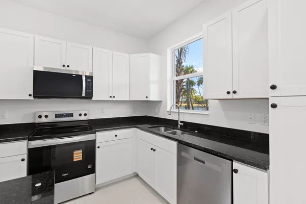 a kitchen with granite countertop a sink and white cabinets