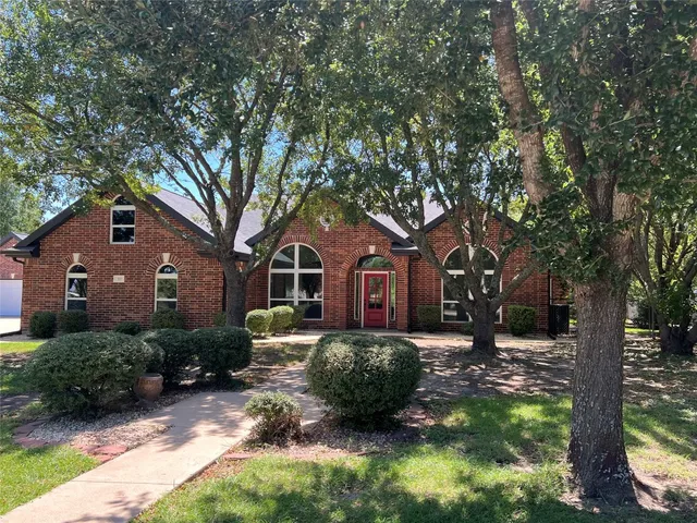 a front view of a house with a yard and large tree