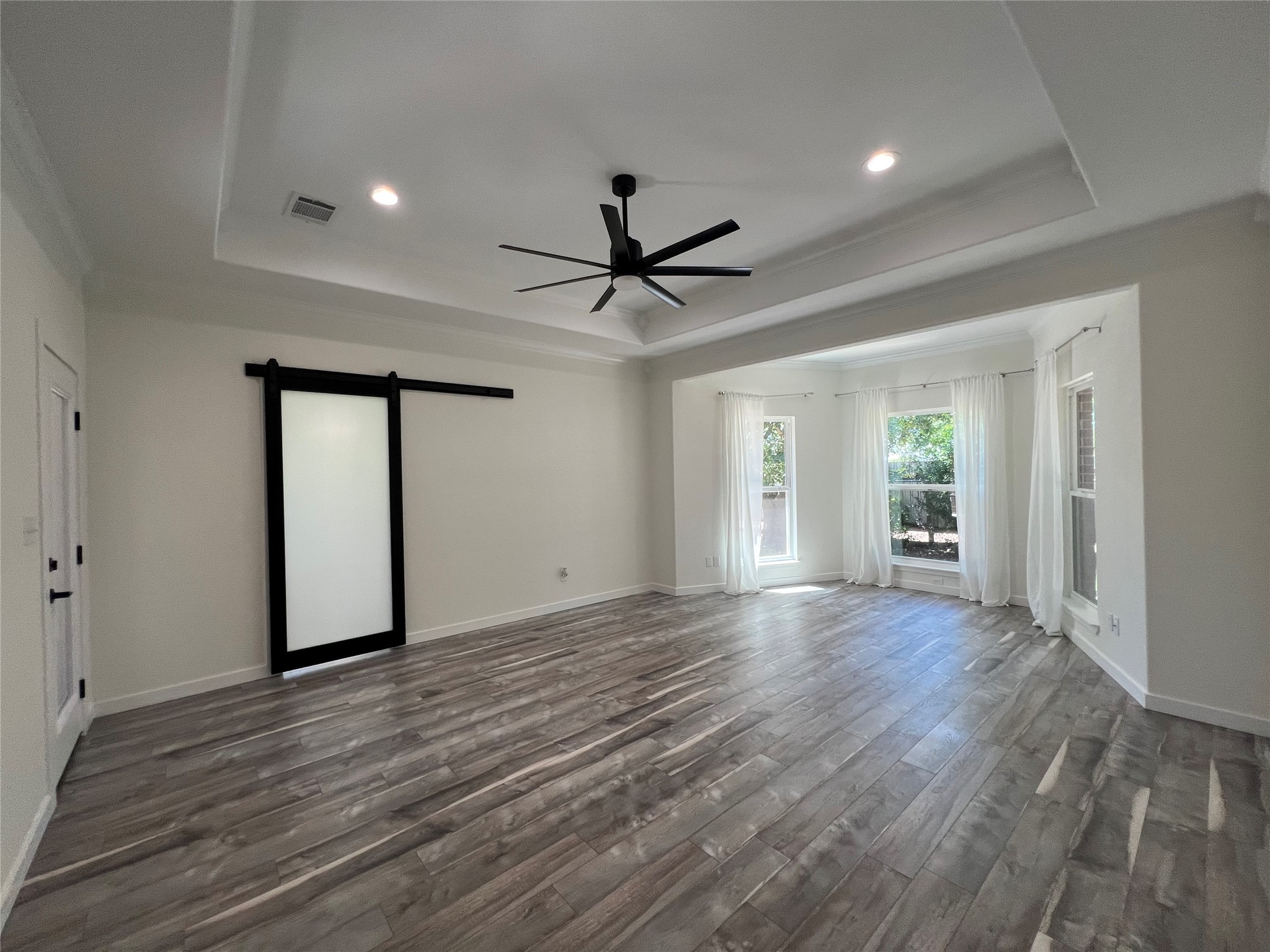 117 Cotton Rows Lane Taylor, TX 76574 - Photo 20 of 35 Owner's suite barn door, ceiling fan, wood finished floors, a coffered ceiling, and recessed lighting