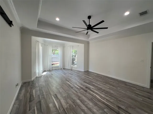 a view of empty room with wooden floor and fan