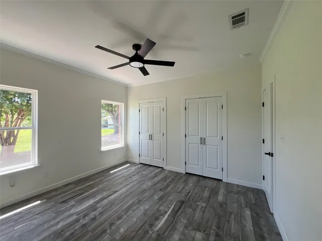 a view of empty room with wooden floor and fan