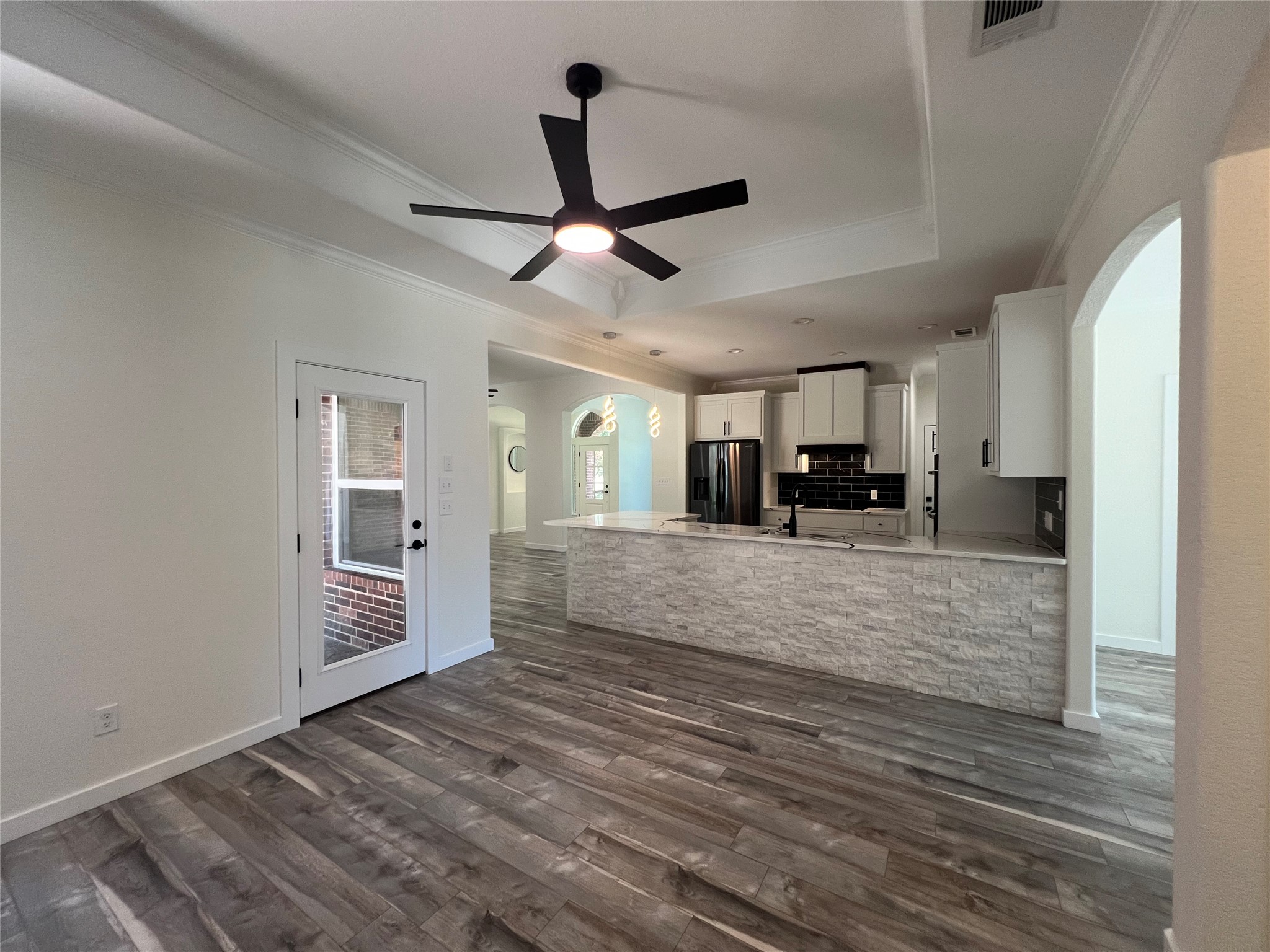 117 Cotton Rows Lane Taylor, TX 76574 - Photo 6 of 35 Kitchen featuring a raised ceiling, arched walkways, a peninsula, white cabinets, and dark wood-style flooring