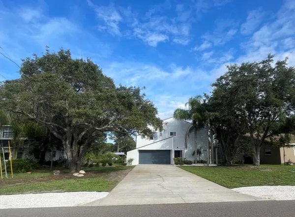 a view of a white house with a big yard and large trees