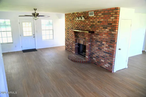an empty room with wooden floor fireplace and windows
