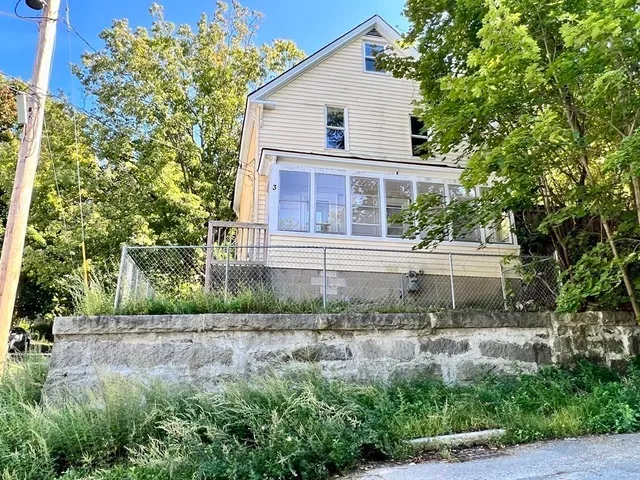 a view of a white house next to a yard with big trees