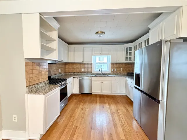 a large kitchen with a center island wooden floor and stainless steel appliances