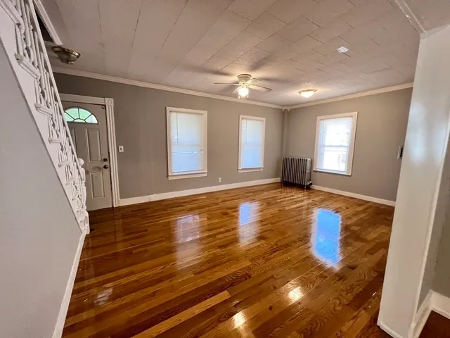 a view of an empty room with wooden floor and stairs