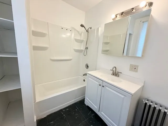 a bathroom with a tub sink and mirror