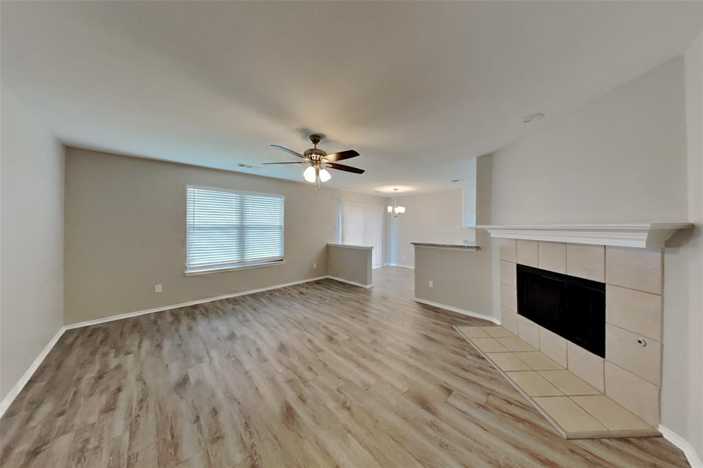 4204 Highgate Road Fort Worth, TX 76244 - Photo 3 of 19 Unfurnished living room with light wood-type flooring, a tiled fireplace, a ceiling fan, and a chandelier