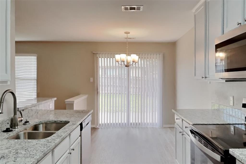 4204 Highgate Road Fort Worth, TX 76244 - Photo 6 of 19 Kitchen with stainless steel appliances, light stone countertops, light wood-style floors, and white cabinets