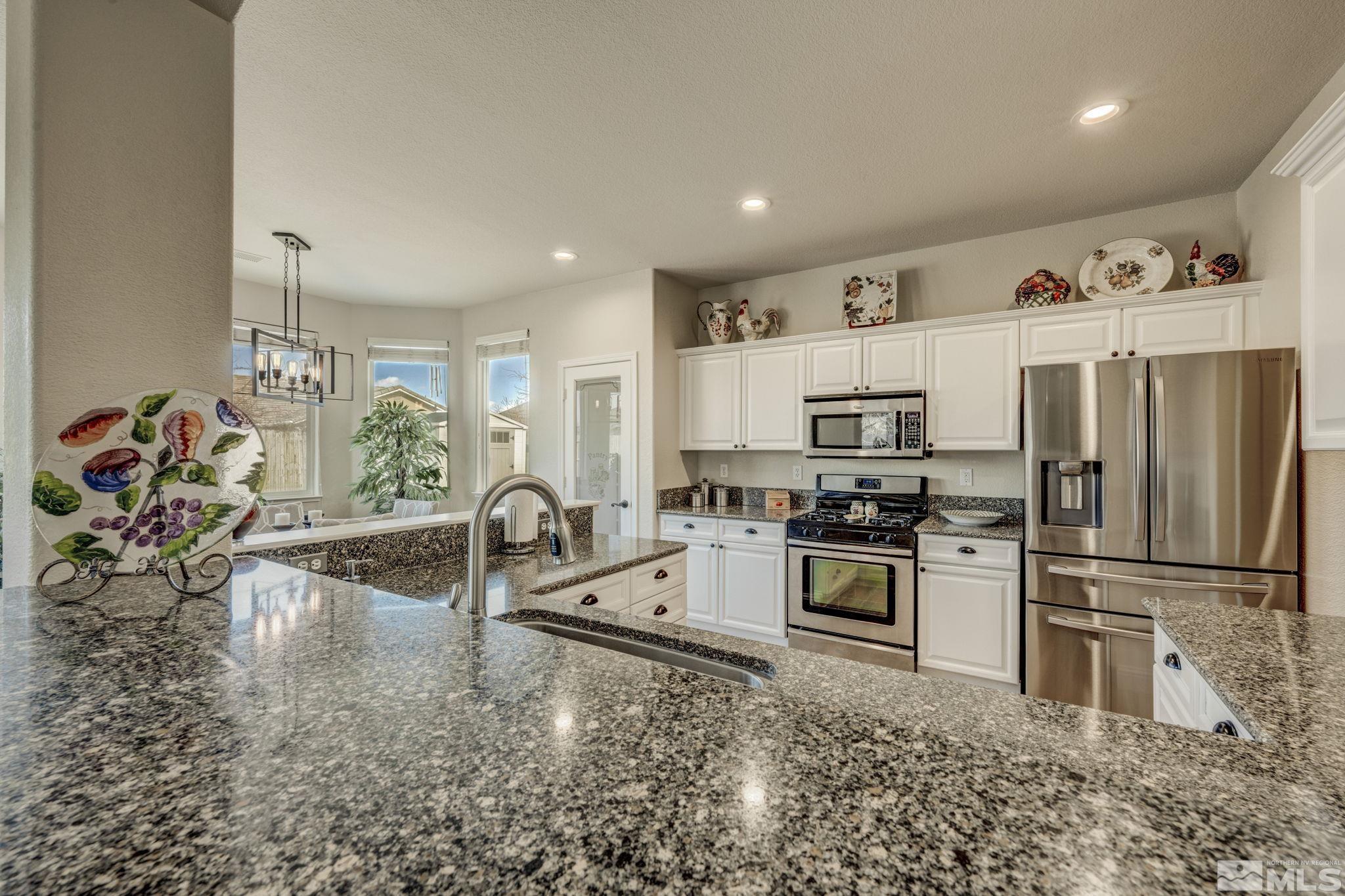 1825 D'Arques Court Reno, NV 89521 - Photo 12 of 40 a kitchen with stainless steel appliances granite countertop a refrigerator a stove and a sink with wooden floor