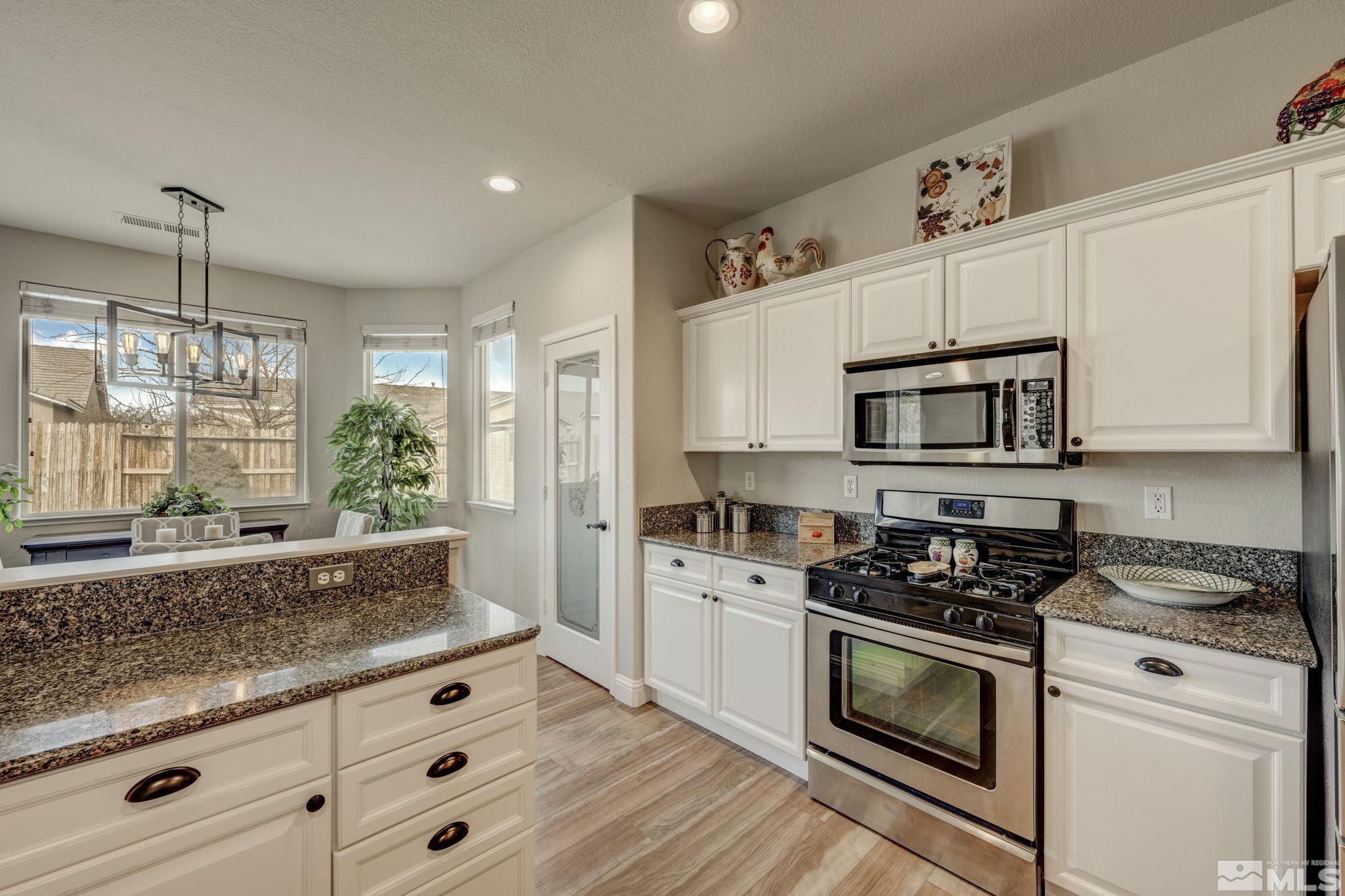 1825 D'Arques Court Reno, NV 89521 - Photo 15 of 40 a kitchen with granite countertop white cabinets and white appliances