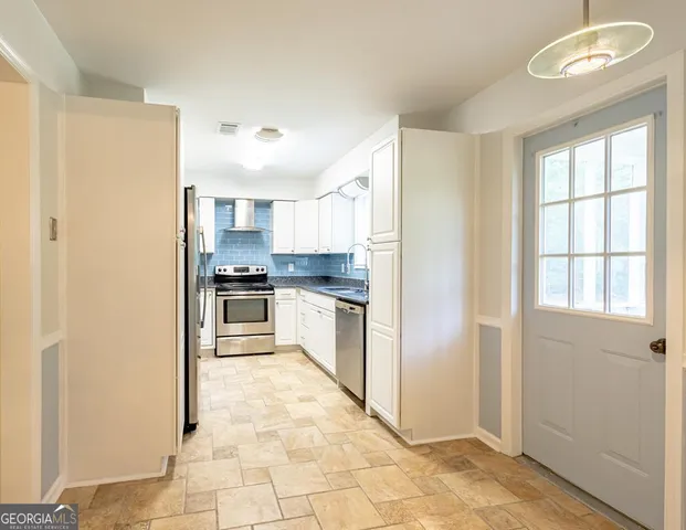 a kitchen with granite countertop a refrigerator and a stove top oven