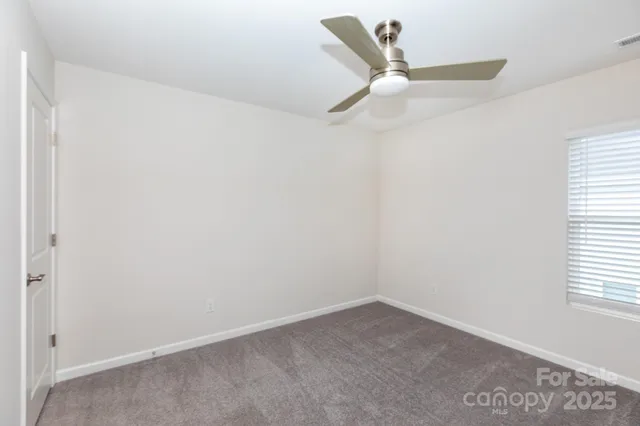 an empty room with a ceiling fan and window