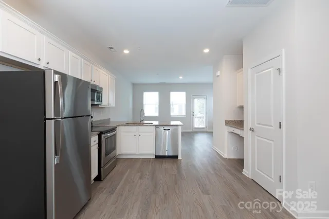 a kitchen with a refrigerator a sink and wooden floor