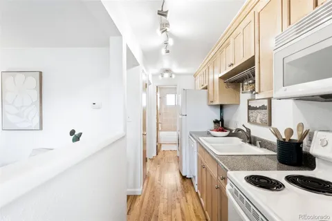 a kitchen with stainless steel appliances a white stove top oven a sink dishwasher and white cabinets with wooden floor