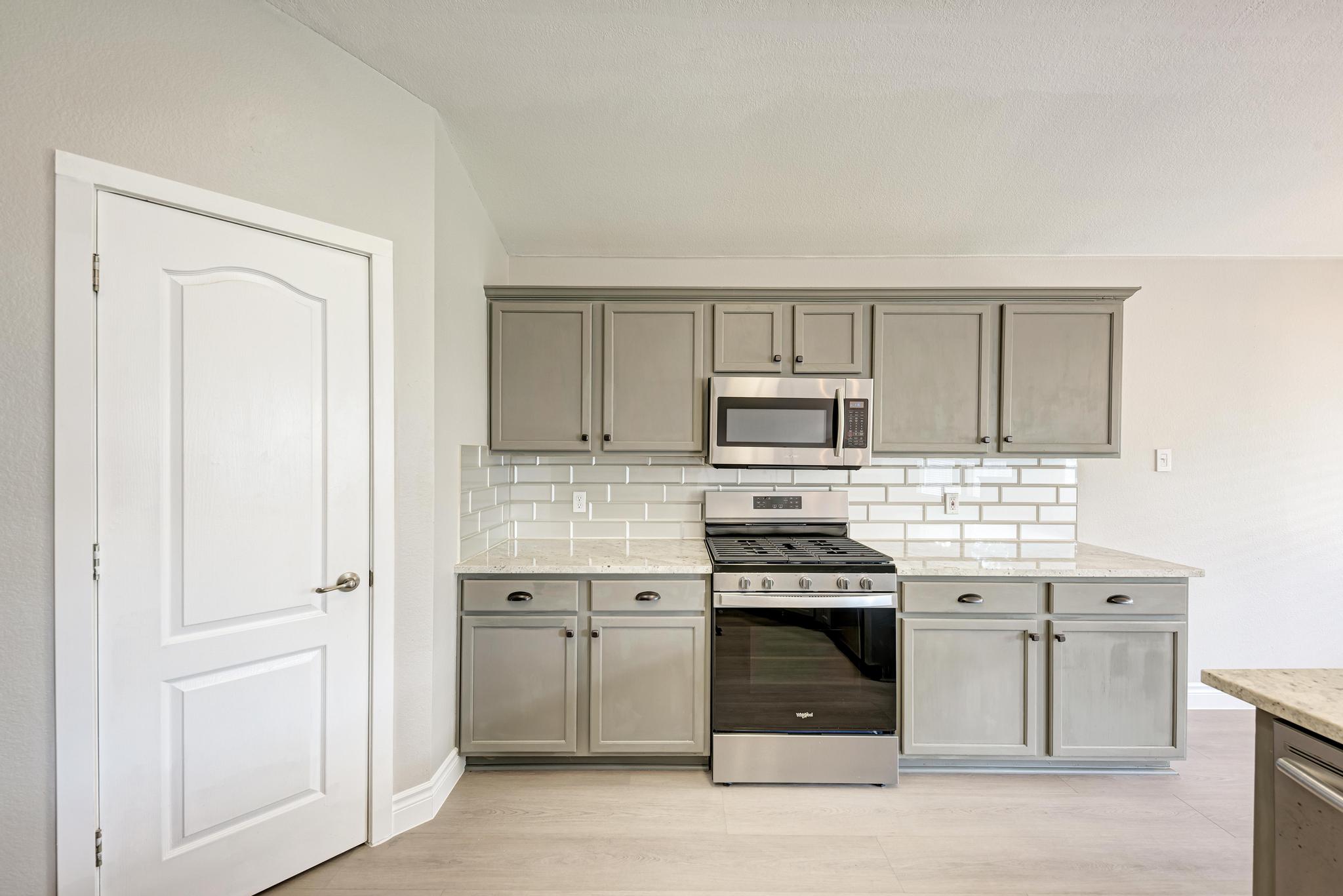 4408 Tello Path Austin, TX 78749 - Photo 19 of 38 Kitchen with appliances with stainless steel finishes, gray cabinetry, backsplash, and light stone countertops