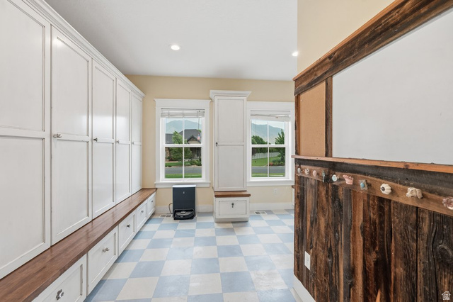 672 Perry Hollow Drive Mapleton, UT 84664 - Photo 35 of 106 Built-in white cabinetry with a wood bench, checkered flooring, and a rustic wood accent wall with decorative knobs