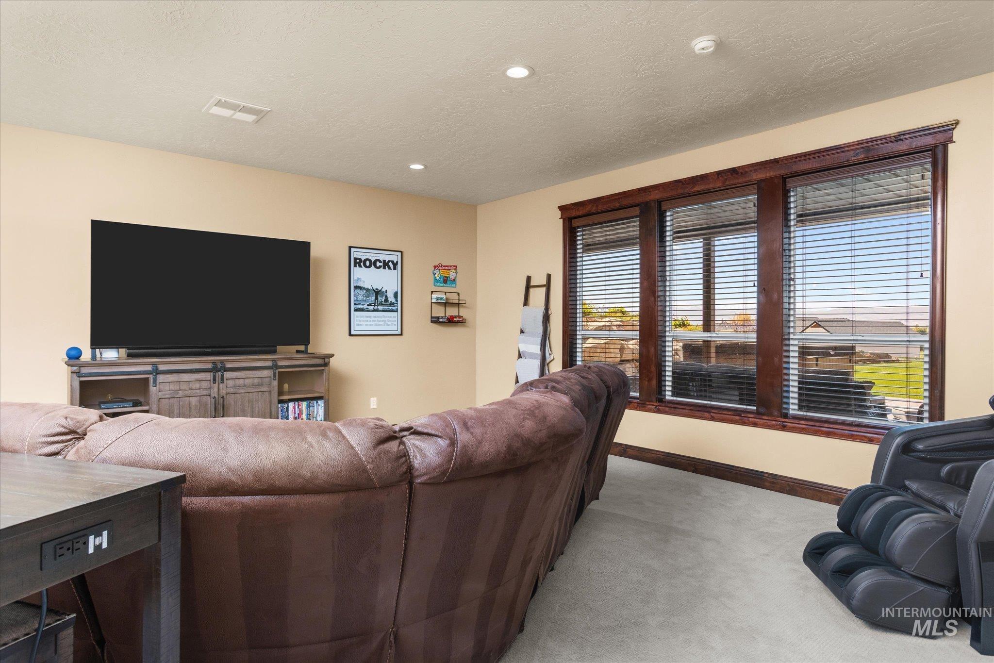 13683 Hockberger Ranch Road Caldwell, ID 83607 - Photo 30 of 50 Recessed lighting, light beige wall color, wood-trim windows, light-tone carpet, and dark wood-finish entertainment console