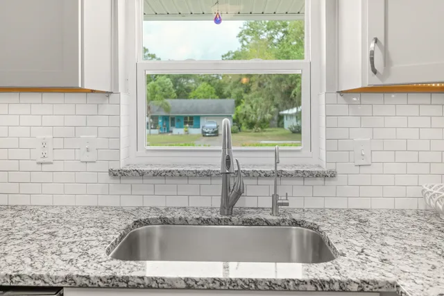 a bathroom with a granite countertop sink and a window