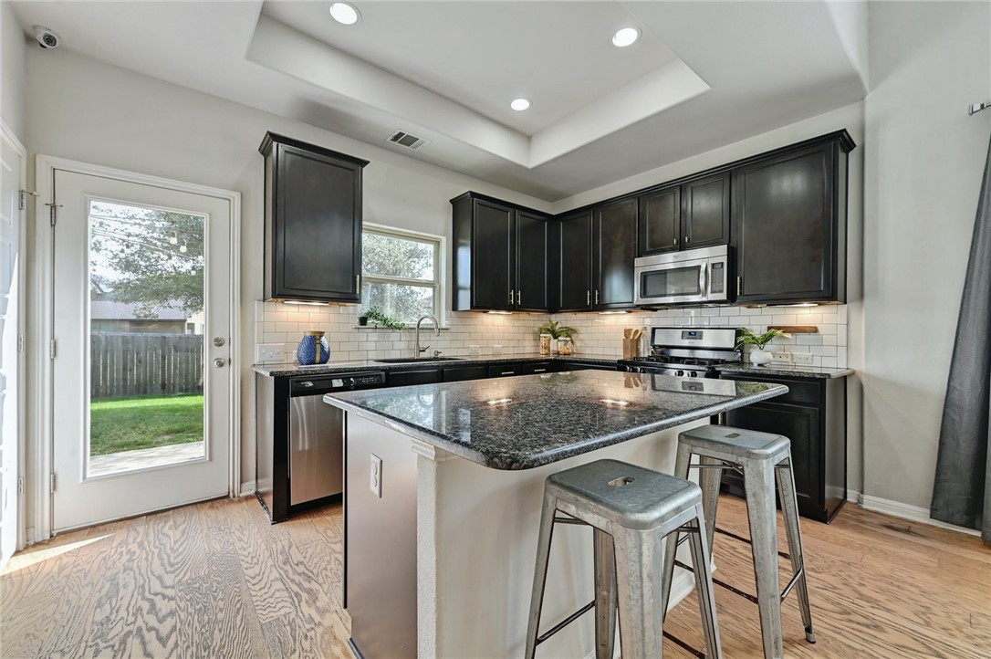 7337 Menchaca Road, Unit 2 Austin, TX 78745 - Photo 1 of 1 a kitchen with kitchen island granite countertop wooden cabinets and a refrigerator